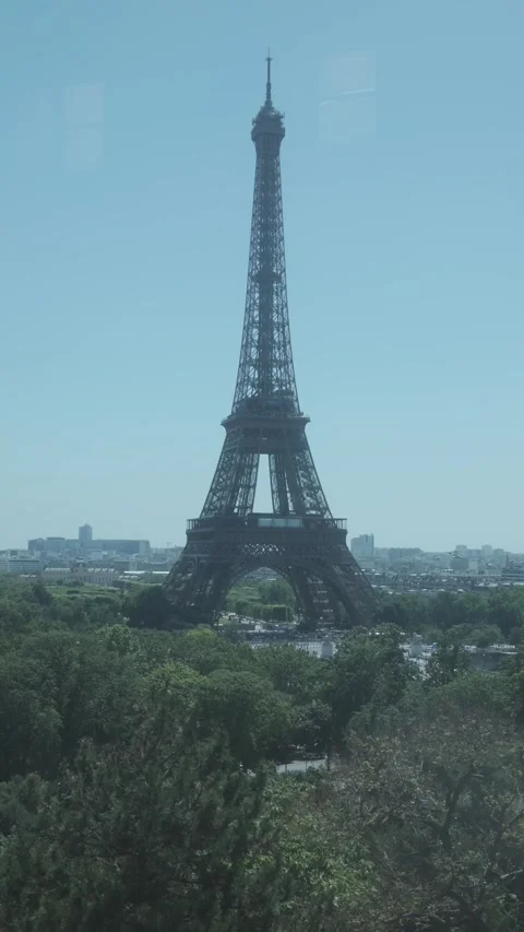 Vertical view of the Eiffel Tower rising above the trees and Paris skyline on a Stock Footage 347833040