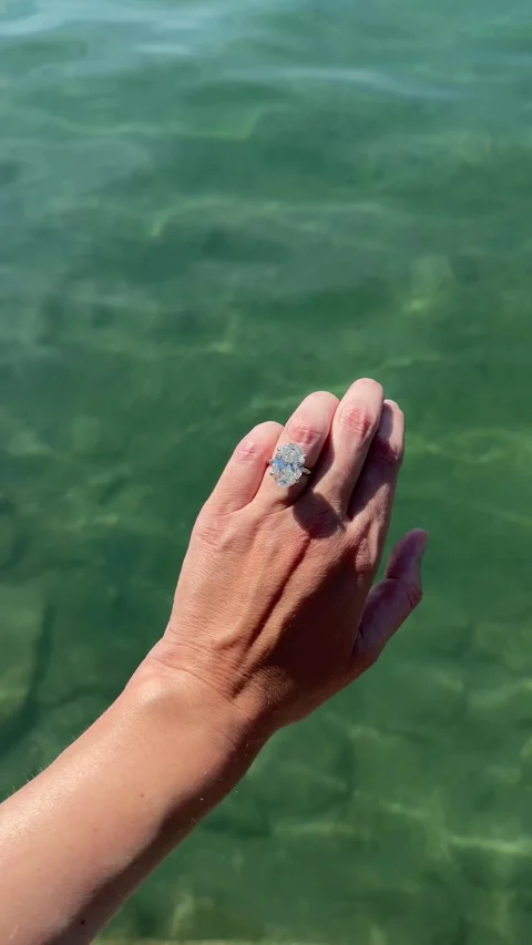 Vertical view of elegant oval diamond engagement ring above sea Stock Footage 319450947