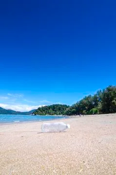 Vertical view empty bottle near the beach, blue sky and white sand Foto stock