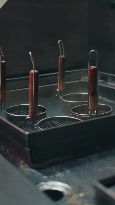 Vertical view of empty metal cooking strainers in hot water in restaurant Stock Footage 333897164