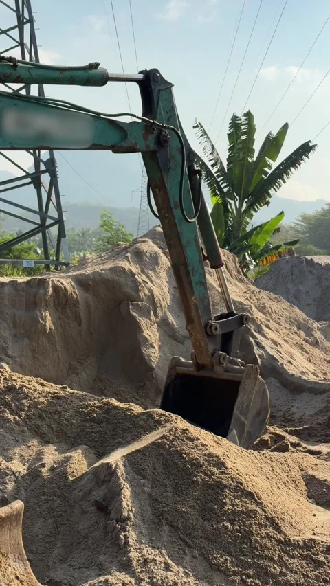 Vertical view of an excavator bucket scooping sand across a construction site Stock Footage 332300544