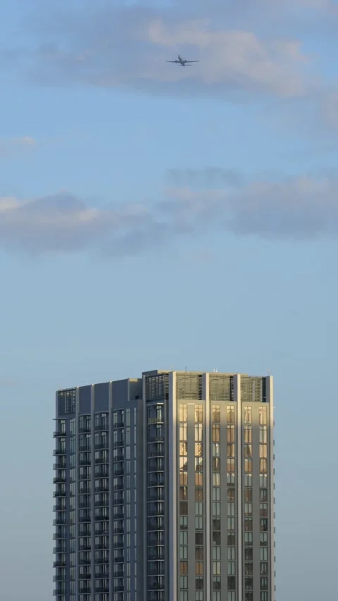 Vertical view of featuring airplane flying above tall building with many windows Stock Footage 293850598