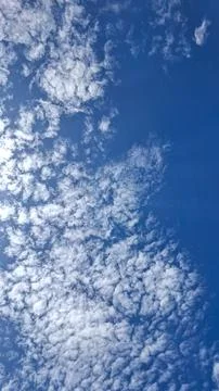Vertical view of fluffy white clouds on a bright blue sky Stock Photos