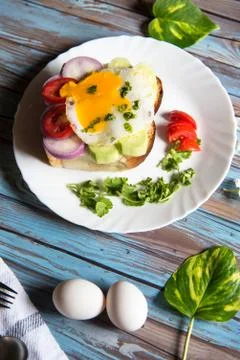 Vertical view of fried eggs with bacon and vegetables on bun bread Stock Photos