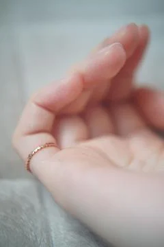 Vertical view of a golden ring on a woman's little finger, on a bright soft back Stock Photos