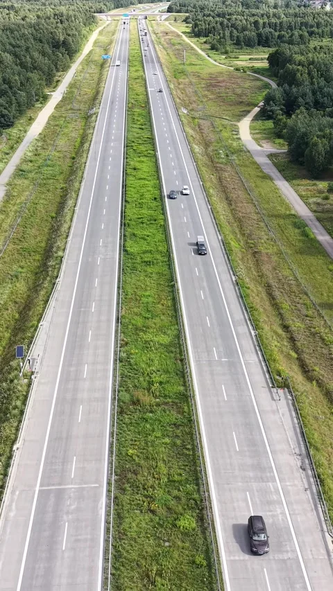 Vertical view. Green forest highway seen from above with passing vehicles Video stock 348630878
