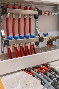 Vertical view of heating manifold and connected pipes inside cabinet. Stock-Fotos