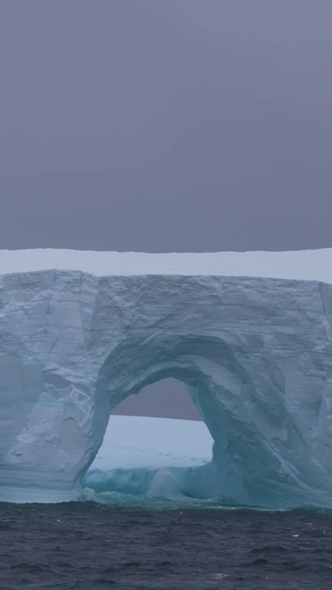 Vertical View of Iceberg and Ocean Sea Waves Breaking on Ice on Cold Misty Day Stock Footage 341327512