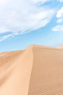 Vertical view of a large sand dune with blue sky in the back and some clouds. Foto stock