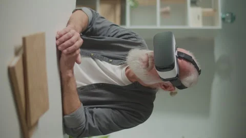 Vertical View.A Modern Old Man in VR Glasses Examines Everything Around. Video stock 250287375