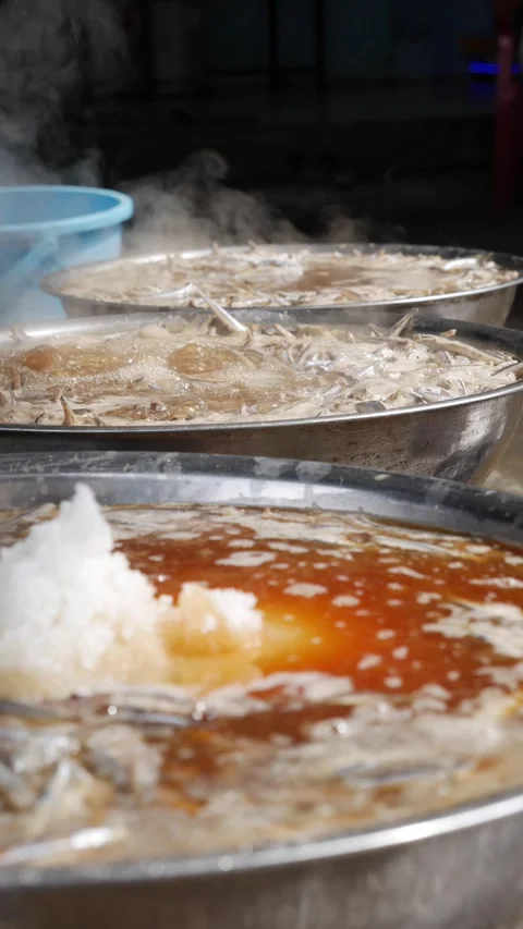 Vertical view of multiple woks filled with boiling liquid heating over flames Stock Footage 331247729