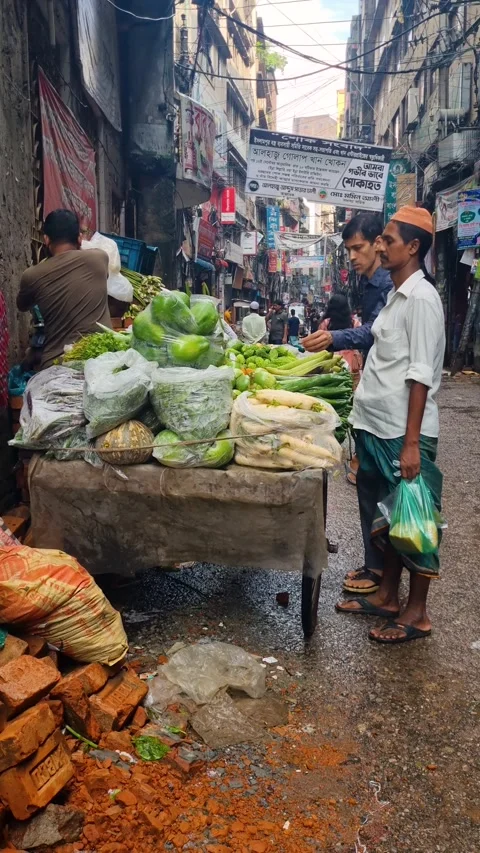 Vertical view of a narrow Old Dhaka street after monsoon rain, with a vegetable Stock Footage 321327328