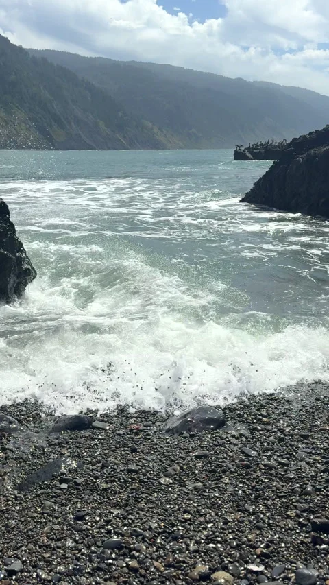 Vertical View of Ocean Tide Rushing Over Dark Pebble Beach Stock-Footage 334231847