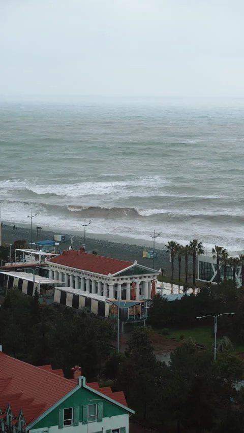 Vertical view of ocean waves hitting coast with grey clouds on background. Stock Footage 180043803