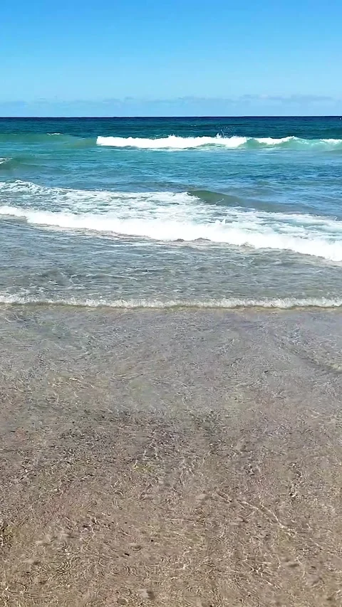 Vertical View of Ocean Waves Rolling onto a Sandy Shoreline 库存影片 329537200