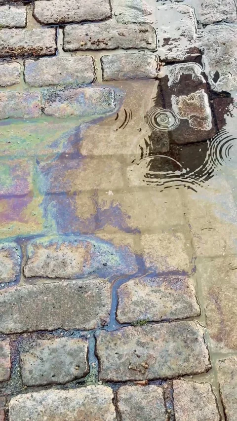 Vertical view of an oily rainbow puddle in the rain Stock Footage 343126908