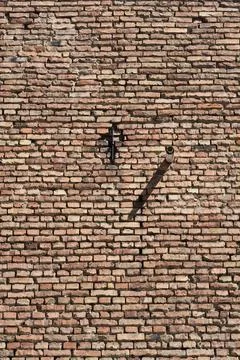 Vertical view of old brick wall with a pipe and metal anchor Stock Photos