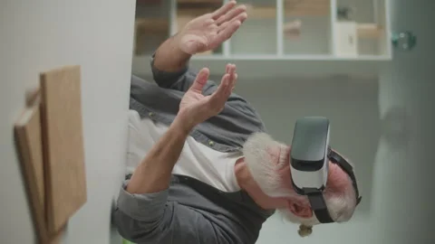 Vertical View.An Old Man in VR Glasses Examines and Touches Everything Around. Video stock 250303170