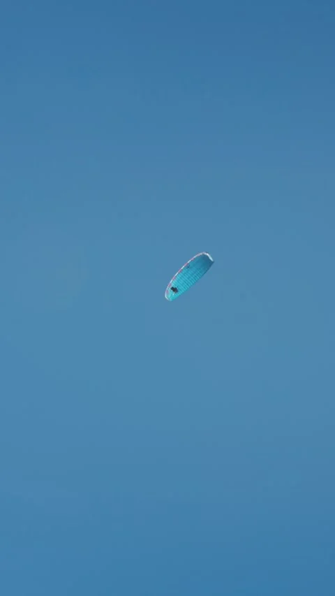 Vertical view of a parachute drifting across a clear blue sky above Marbella Stock Footage 327509863