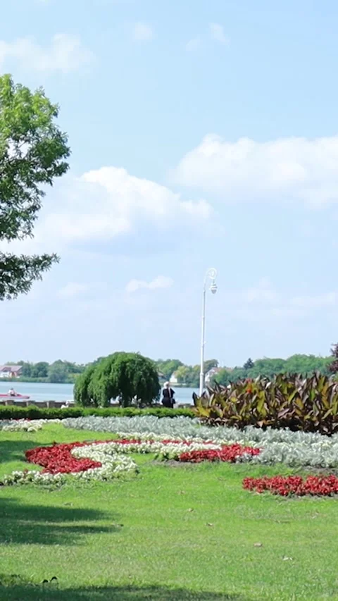 Vertical View of Park Lawn with Flower Beds by the Lake - 9:16 스톡 동영상 334891708