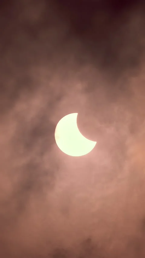 Vertical View of Partial Solar Eclipse Behind Dramatic Clouds in Golden Light Stock Footage 320265477