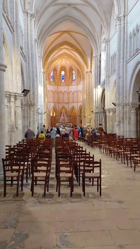 Vertical view of people inside a historic church interior with wooden chairs in Stock Footage 348600579