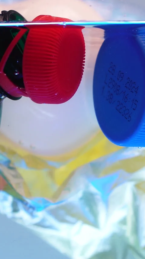 Vertical View, Plastic Bottles With Attached Caps and Bags in Water, Stock Footage 289270620