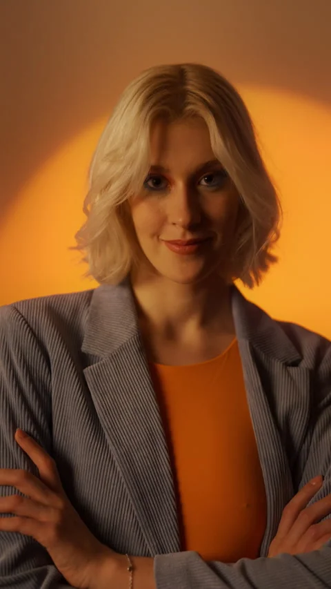 Vertical view of portrait young elegant woman in jacket posing over orange Stock Footage 252689187