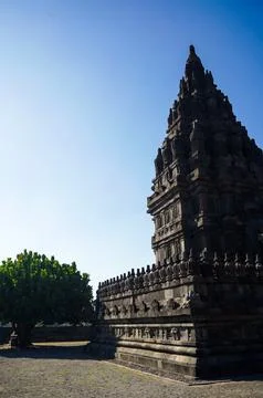 Vertical view of a Prambanan Temple tower rising beside the open stone cour.. Stock-Fotos