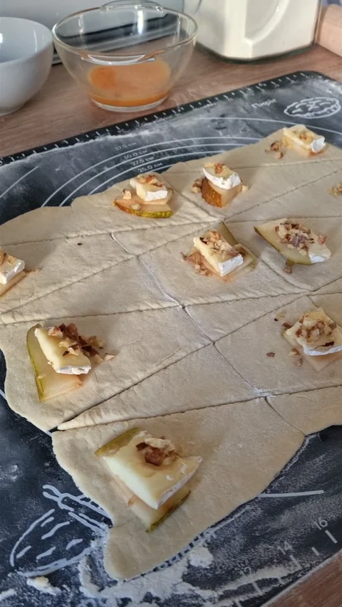 Vertical view of raw croissant dough triangles topped with pear brie and walnuts Stock-Footage 347747403