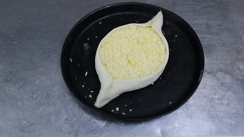 Vertical view raw khachapuri with cheese turns around on plate in the restaurant Stock Footage 128661150