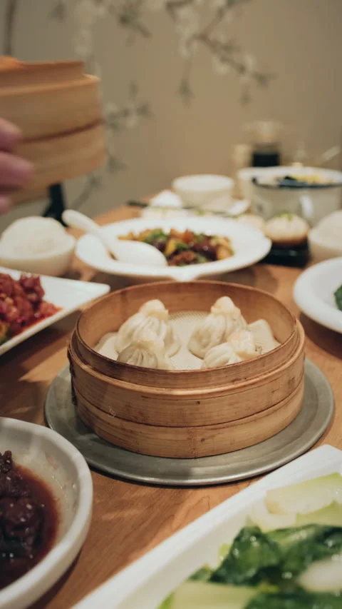 Vertical view of restaurant table with Chinese dishes and bamboo steamer being Stock Footage 333898045