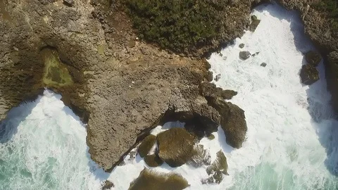 Vertical view of rock cliff beach with foamy sea wave splashing Stock Footage 114541722
