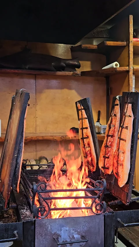 Vertical view of salmon fillets smoking on wooden boards over open fire. Stock-Footage 347884595