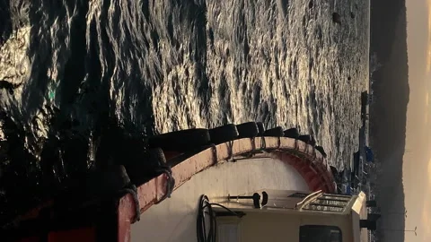 Vertical: View of sea bay at sunset with boat swaying on waves Vidéo 239720188