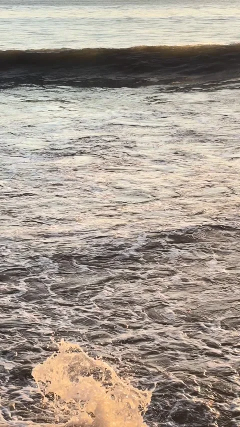 Vertical View of Sea Waves and White Foam Splashing Under Golden Sunset Light Stock Footage 345953978