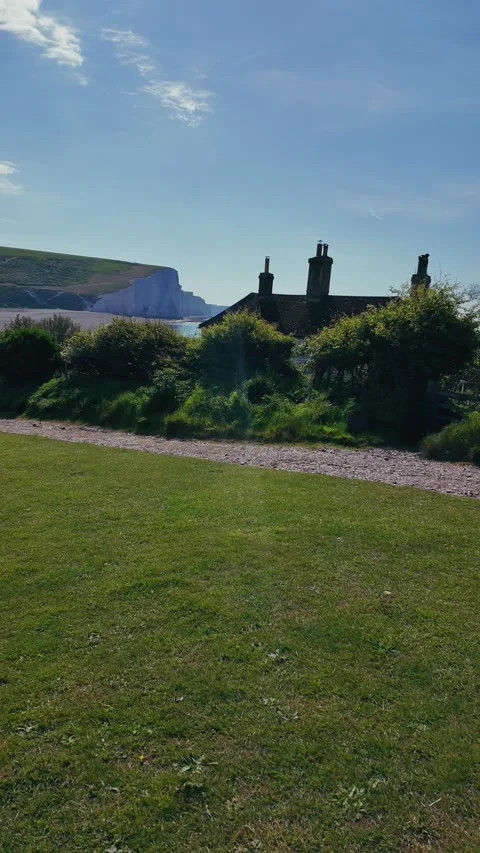 Vertical view of seaside walking path with cottage and distant chalk cliffs Stock Footage 309769009
