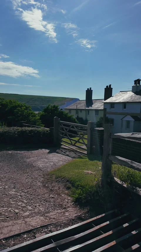 Vertical view of seaside walking path with cottage and distant chalk cliffs Stock Footage 309769024