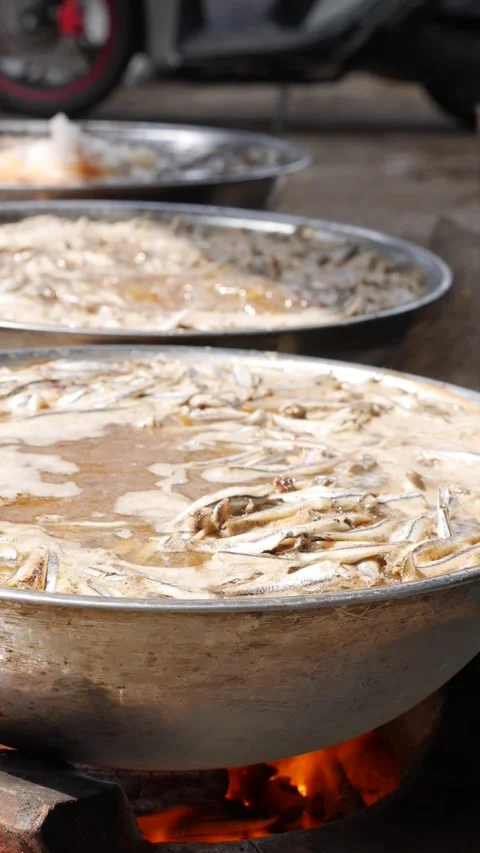 Vertical view of several woks cooking sauce over open flames where hot liquid Stock Footage 331078907