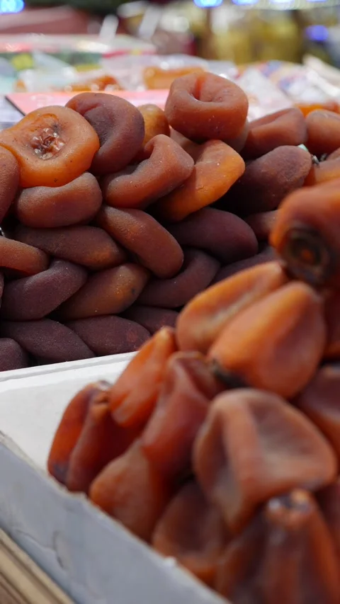 Vertical view shows dried persimmons stacked high on a market surface forming a Видео 334615674