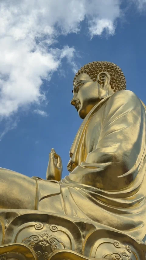 Vertical view shows golden Buddha statue close with raised hand near face Vidéo 333197827