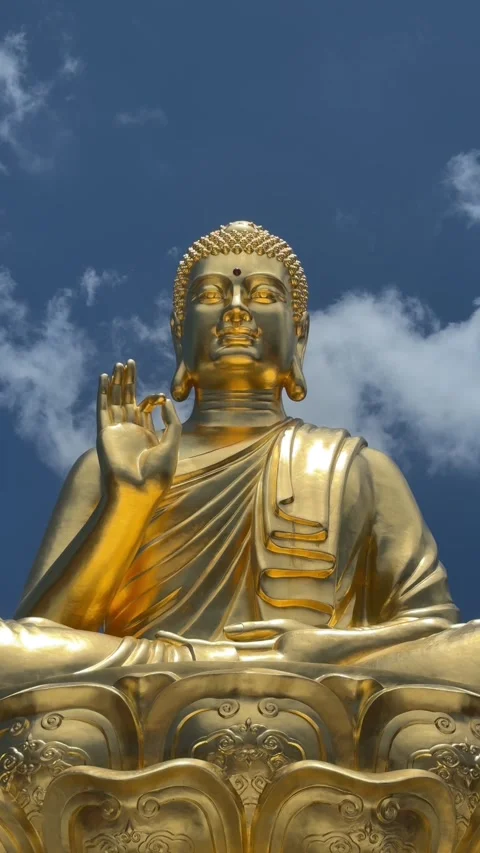 Vertical view shows golden Buddha statue seated on decorated base against cloudy Stock Footage 334854306