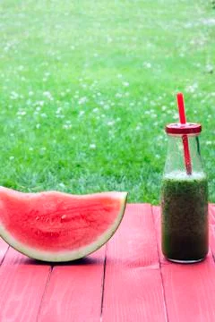 A vertical view of a slice of watermelon and a smoothy in a bottle Stock Photos