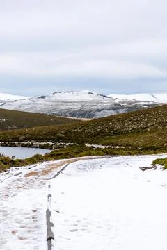 Vertical view of a snowy path between mountains and with a lagoon Stock Photos