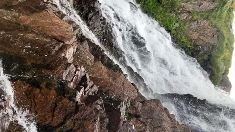 Vertical view of splashing water from a small waterfall to a rocky bottom Video stock 231511981