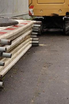 Vertical view of stacked construction barriers and yellow utility machine Stock Photos