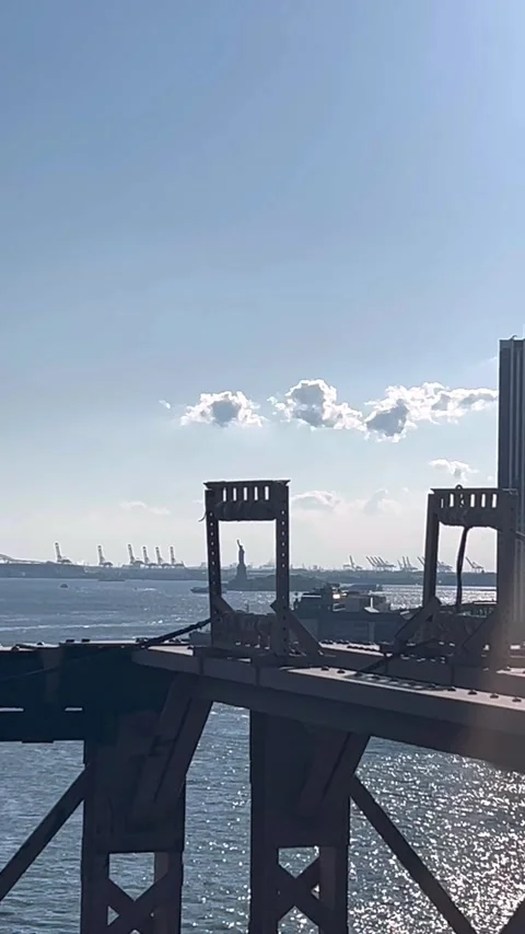 Vertical View of Statue of Liberty Framed by Bridge Structure in New York Harbor Stock Footage 328877456
