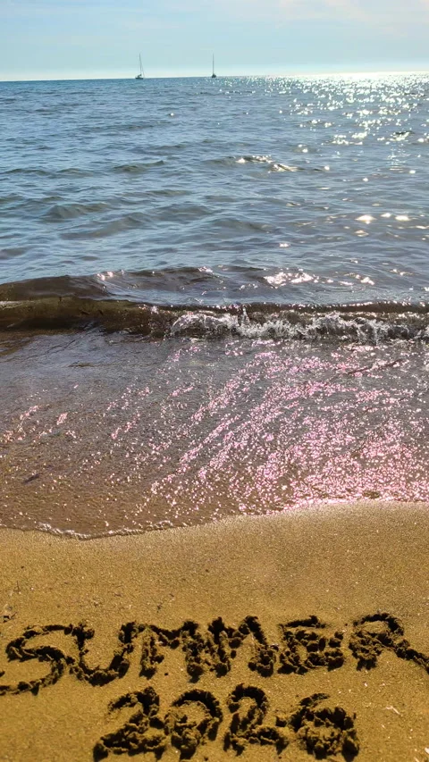 Vertical view of summer 2026 text on beach sand at golden hour in slow motion Video stock 335758101