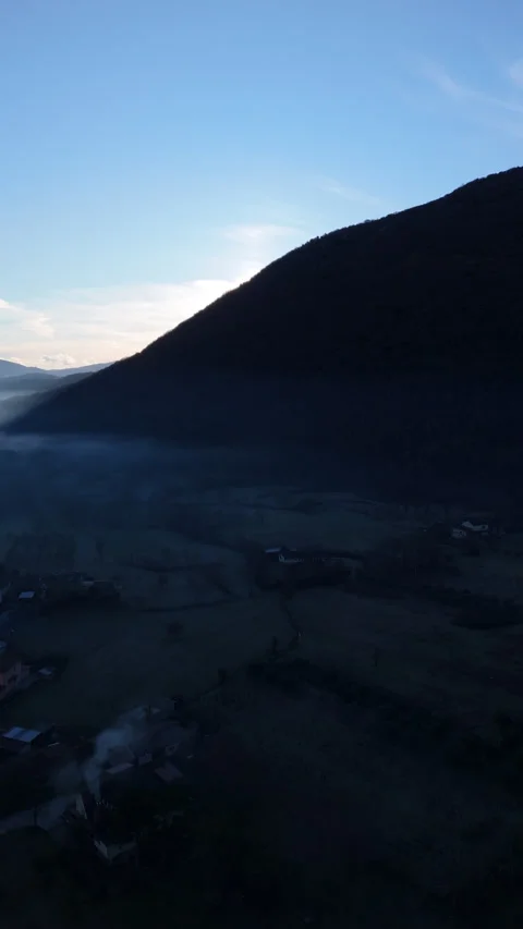 Vertical view of sun rising behind a mountain peak with morning mist Video stock 328123994