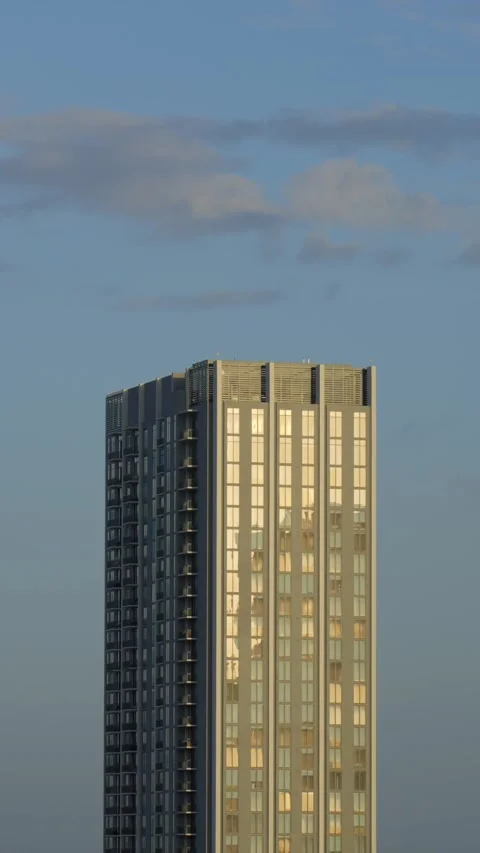 Vertical view of a tall building with many windows. Construction illuminated by Stock Footage 293851610